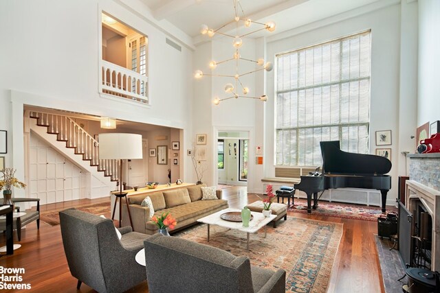 living room with a chandelier, wood finished floors, a high ceiling, stairway, and a fireplace