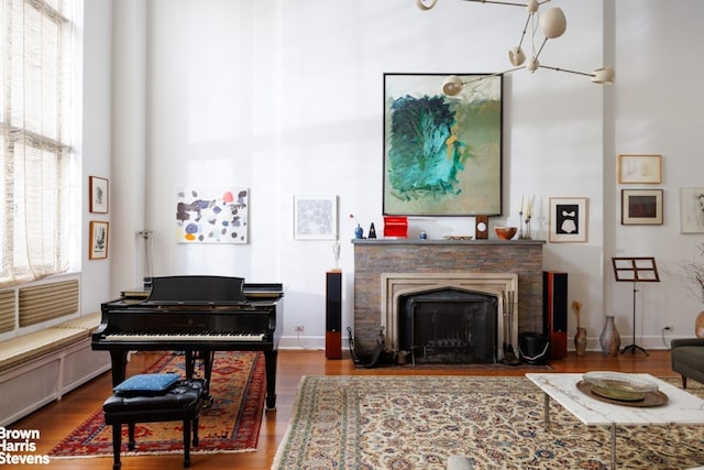 living area featuring a towering ceiling, baseboards, wood finished floors, and a fireplace