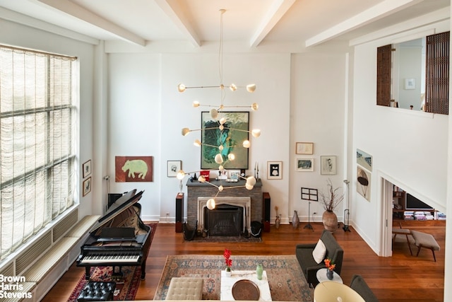 living room with a fireplace with flush hearth, baseboards, a chandelier, beamed ceiling, and wood finished floors