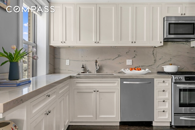 75 Bank St Unit 3K, New York City, NY 10014 - kitchen featuring stainless steel appliances, a sink, white cabinetry, and backsplash