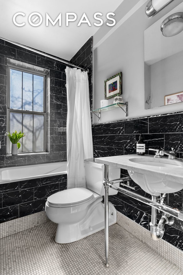 75 Bank St Unit 3K, New York City, NY 10014 - bathroom with tile walls, tiled shower / bath, toilet, tile patterned floors, and a sink