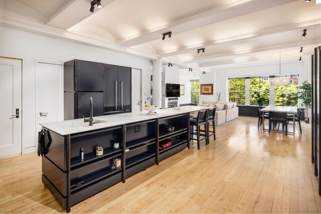 kitchen featuring beam ceiling, a spacious island, black refrigerator, dark cabinets, and light countertops