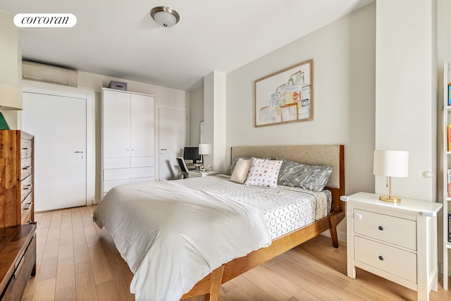 bedroom featuring a wall unit AC, light wood-type flooring, and a closet