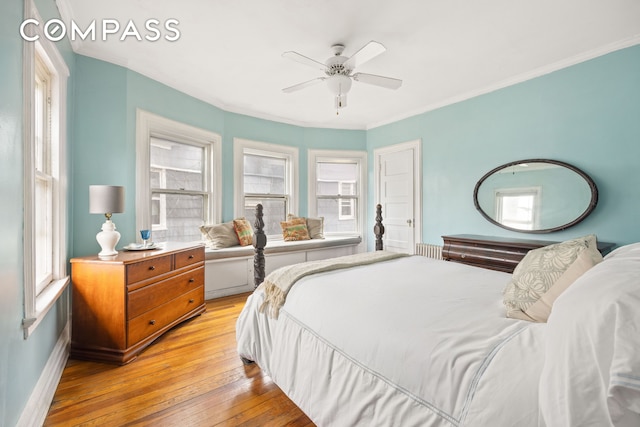 bedroom featuring baseboards, crown molding, multiple windows, and light wood-style flooring