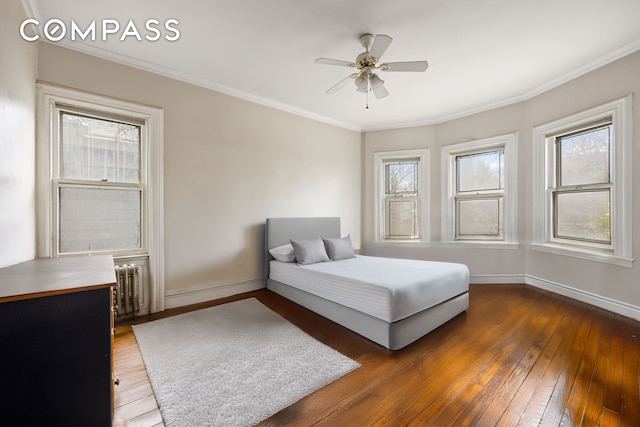 bedroom featuring radiator heating unit, hardwood / wood-style flooring, baseboards, and multiple windows