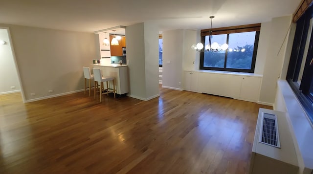 515 E 72nd St Unit 4B, New York City, NY 10021 - kitchen with dark wood-style flooring, a chandelier, a kitchen bar, a peninsula, and baseboards