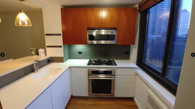 515 E 72nd St Unit 4B, New York City, NY 10021 - kitchen featuring appliances with stainless steel finishes, a sink, light countertops, dark wood-type flooring, and decorative light fixtures