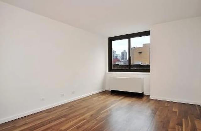 515 E 72nd St Unit 4B, New York City, NY 10021 - spare room with baseboards, dark wood finished floors, and radiator