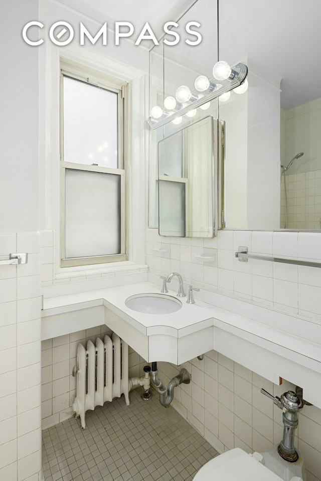 156 E 79th St Unit 9C, New York City, NY 10075 - bathroom featuring tile walls, tile patterned floors, radiator heating unit, a sink, and toilet