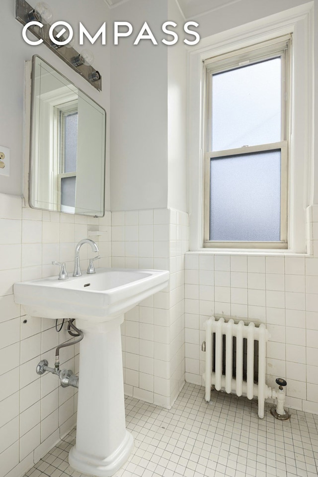 156 E 79th St Unit 9C, New York City, NY 10075 - half bathroom featuring radiator, tile walls, tile patterned floors, and a wainscoted wall