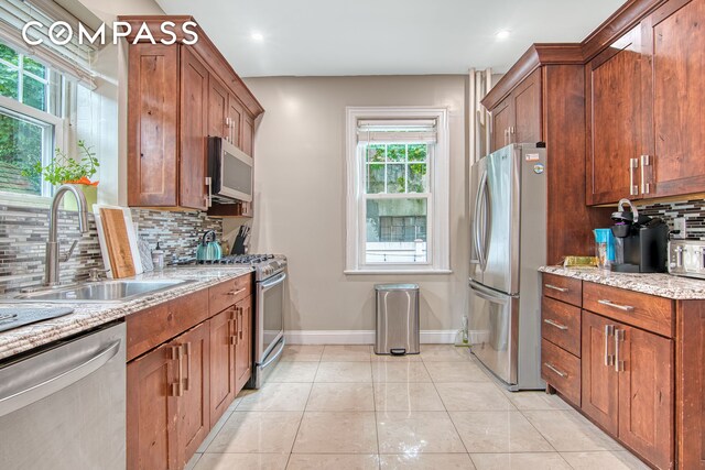 232 Maple St, New York City, NY 11225 - kitchen with appliances with stainless steel finishes, a sink, tasteful backsplash, baseboards, and light stone counters