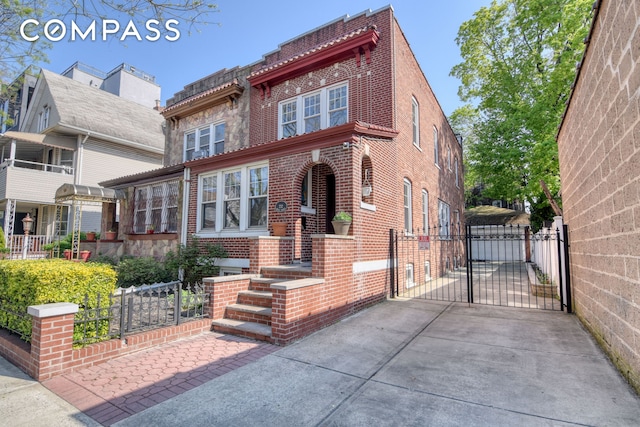 view of front of house with fence, a gate, and brick siding
