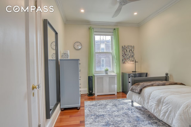 bedroom with recessed lighting, radiator heating unit, wood finished floors, crown molding, and baseboards