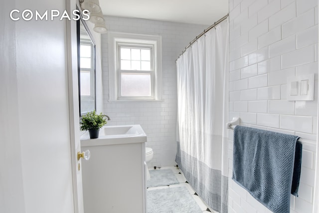 full bath with toilet, vanity, a shower with shower curtain, and tile walls