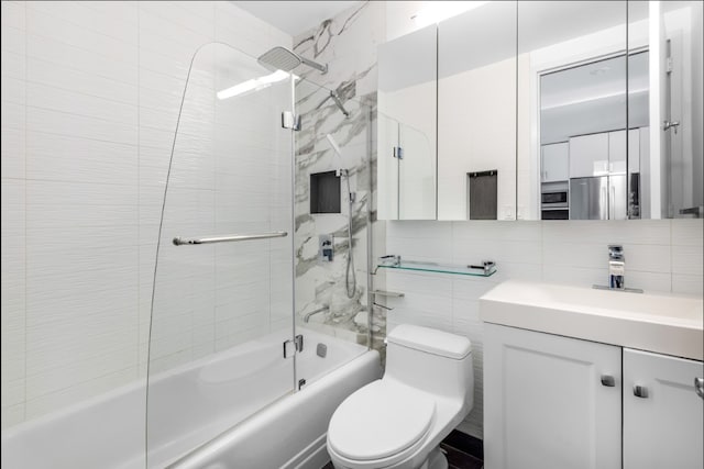 bathroom featuring tile walls, bath / shower combo with glass door, vanity, and toilet