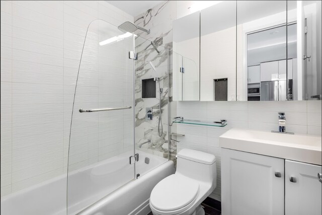 full bath with vanity, combined bath / shower with glass door, toilet, and tile walls
