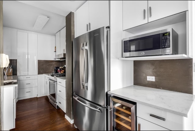 kitchen with appliances with stainless steel finishes, tasteful backsplash, dark wood finished floors, and beverage cooler
