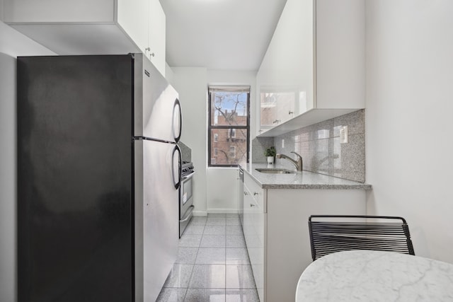 kitchen with a sink, appliances with stainless steel finishes, backsplash, white cabinetry, and granite tiled floors