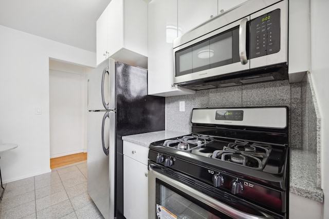 kitchen featuring stainless steel appliances, backsplash, white cabinets, and baseboards