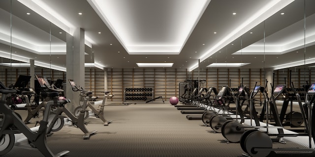 gym with a tray ceiling, recessed lighting, and light colored carpet