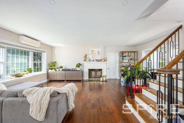 72-03 Ingram St Unit H0Use, New York City, NY 11375 - living room with a wall mounted AC, wood finished floors, stairs, and a fireplace
