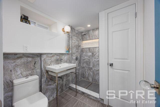 72-03 Ingram St Unit H0Use, New York City, NY 11375 - bathroom featuring a tile shower, tile walls, and toilet