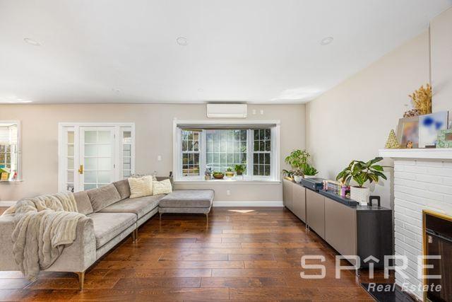 72-03 Ingram St Unit H0Use, New York City, NY 11375 - living area with an AC wall unit, wood-type flooring, baseboards, and a brick fireplace