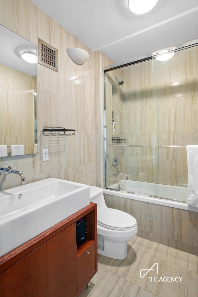 full bath featuring tiled shower / bath, vanity, and toilet
