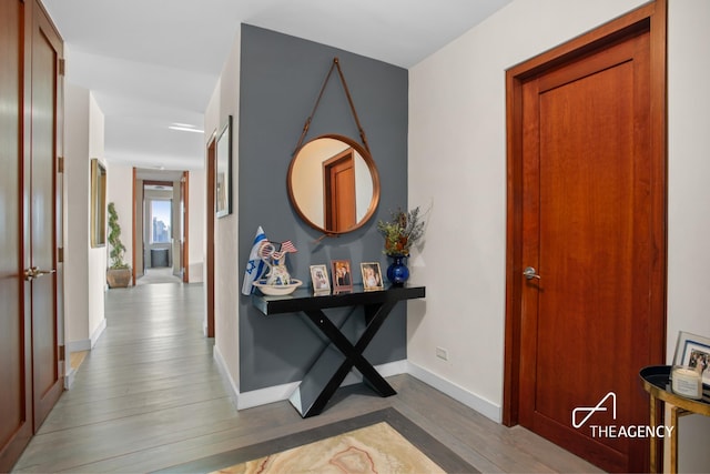 corridor with wood finished floors and baseboards