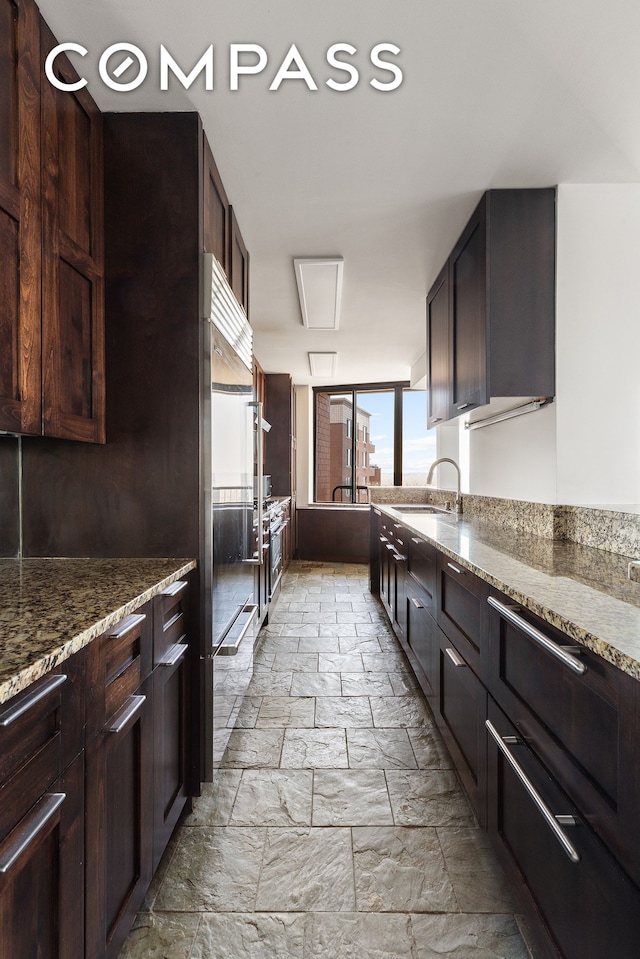 380 Rector Pl Unit 7Lmn, New York City, NY 10280 - kitchen featuring stone tile flooring, dark stone countertops, high end fridge, and dark brown cabinetry