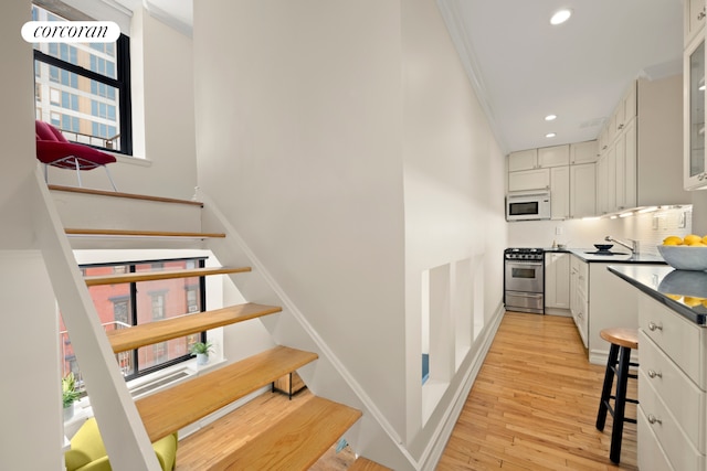 stairway featuring wood finished floors, recessed lighting, ornamental molding, and baseboards