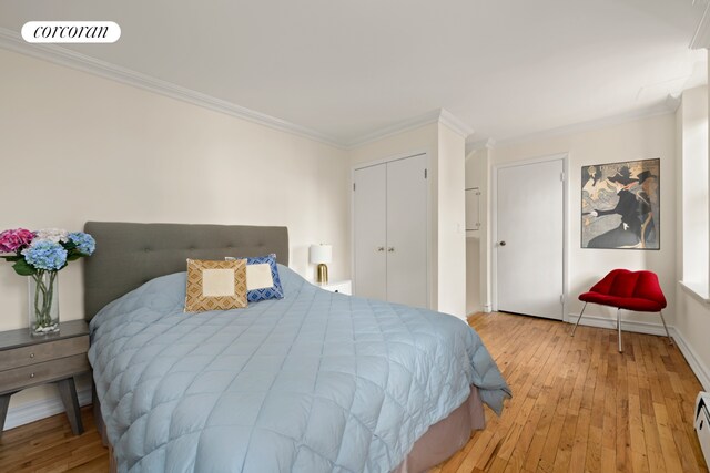 160 E 26th St Unit 5E, New York City, NY 10010 - bedroom with light wood-style flooring, a baseboard radiator, crown molding, and baseboards