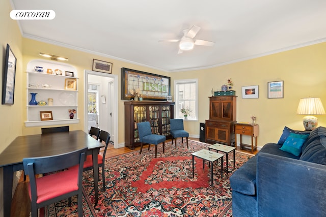 living area with ornamental molding, a ceiling fan, and wood finished floors