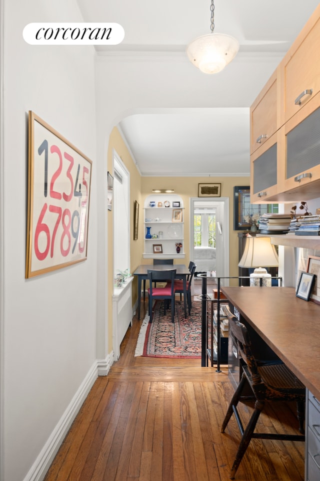 dining room with crown molding, hardwood / wood-style floors, baseboards, an office area, and arched walkways