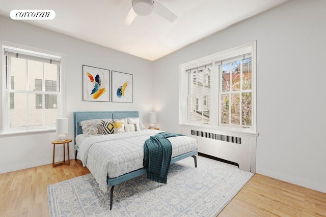 bedroom with radiator, wood finished floors, a ceiling fan, and baseboards