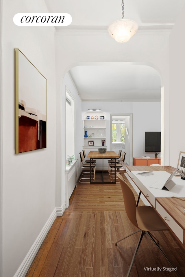 corridor featuring arched walkways, wood finished floors, and baseboards