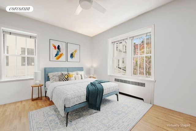 bedroom featuring radiator, wood finished floors, baseboards, and a ceiling fan