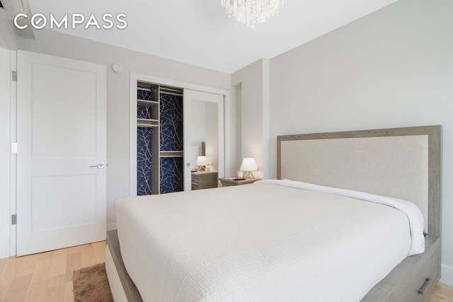 bedroom featuring a closet, wood finished floors, and a notable chandelier
