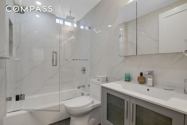 bathroom featuring a combined bath / shower with rainfall shower, vanity, toilet, tile walls, and backsplash