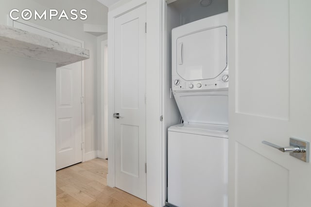 laundry area featuring laundry area, light wood-style flooring, and stacked washing maching and dryer