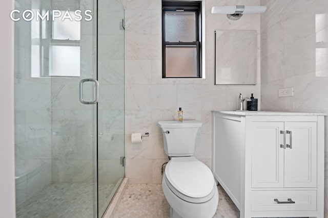 full bath featuring a stall shower, tile walls, toilet, and vanity