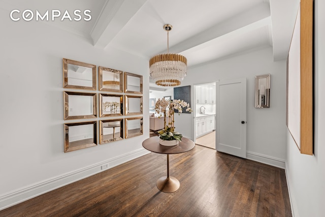 foyer featuring a chandelier, beam ceiling, wood finished floors, ornamental molding, and baseboards