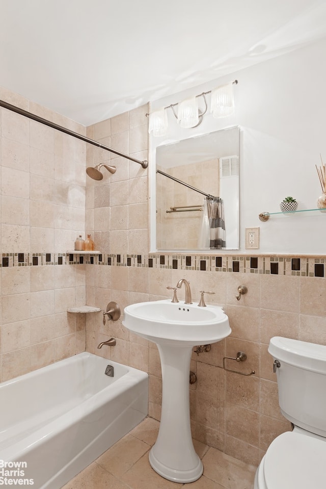 full bath with tile walls, tile patterned floors, toilet, and shower / tub combo