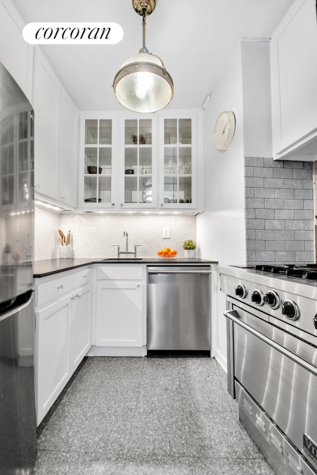 116 Pinehurst Ave Unit H14, New York City, NY 10033 - kitchen with appliances with stainless steel finishes, backsplash, white cabinetry, dark countertops, and hanging light fixtures