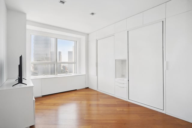 146 W 57th St Unit 53A, New York City, NY 10019 - unfurnished bedroom featuring light wood finished floors and a closet