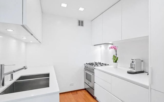 146 W 57th St Unit 53A, New York City, NY 10019 - kitchen with stainless steel range, white cabinets, a sink, light countertops, and recessed lighting