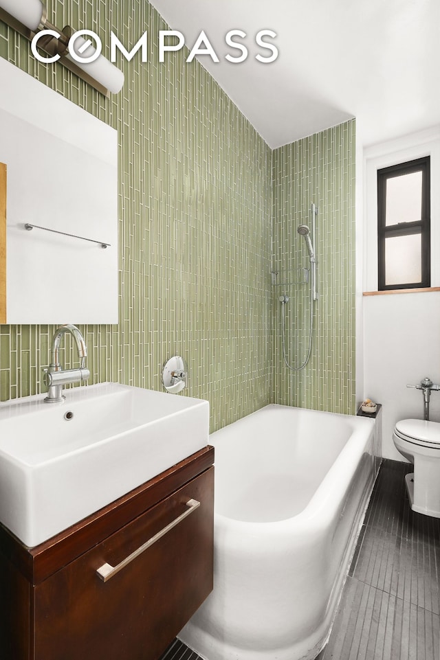 full bath with toilet, tile walls, vanity, bathtub / shower combination, and tasteful backsplash