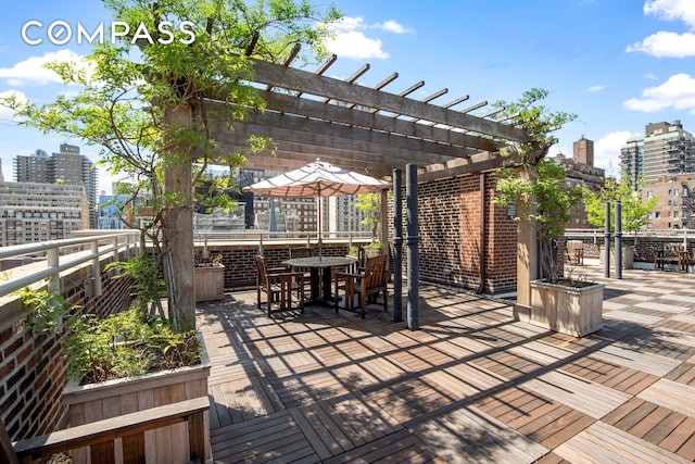 wooden terrace featuring a pergola, outdoor dining space, and a city view