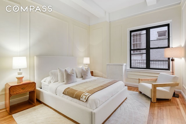 bedroom featuring wood-type flooring and a decorative wall