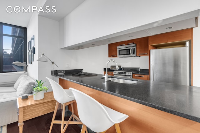 1485 5th Ave Unit 13D, New York City, NY 10035 - kitchen with stainless steel appliances, dark countertops, brown cabinets, modern cabinets, and a peninsula